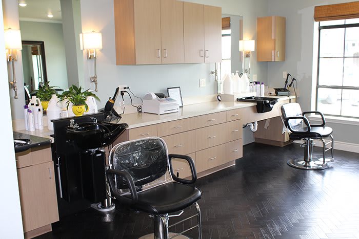 A modern salon interior featuring chairs, mirrors, and a hair washing station.