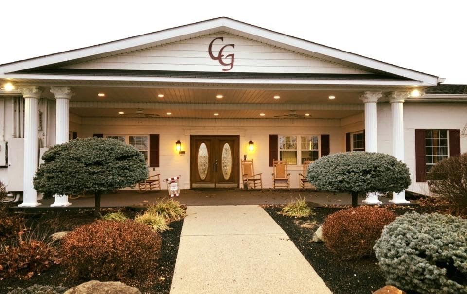 A welcoming building entrance with neatly trimmed shrubs and rocking chairs on the porch.