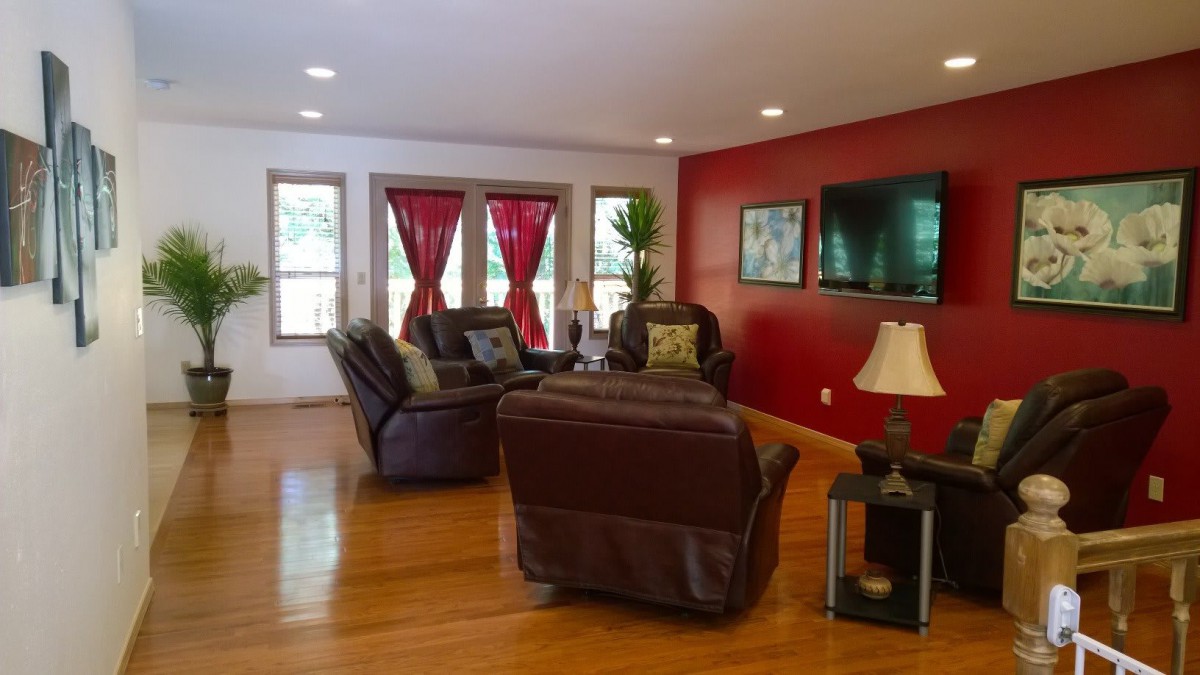 A cozy living room with leather seating, a red accent wall, and natural light.