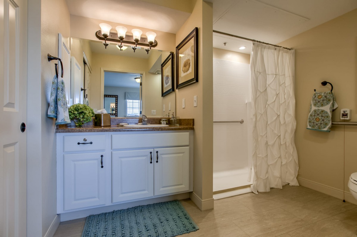 A well-lit bathroom featuring a vanity with a mirror, sink, and a shower area with a curtain.