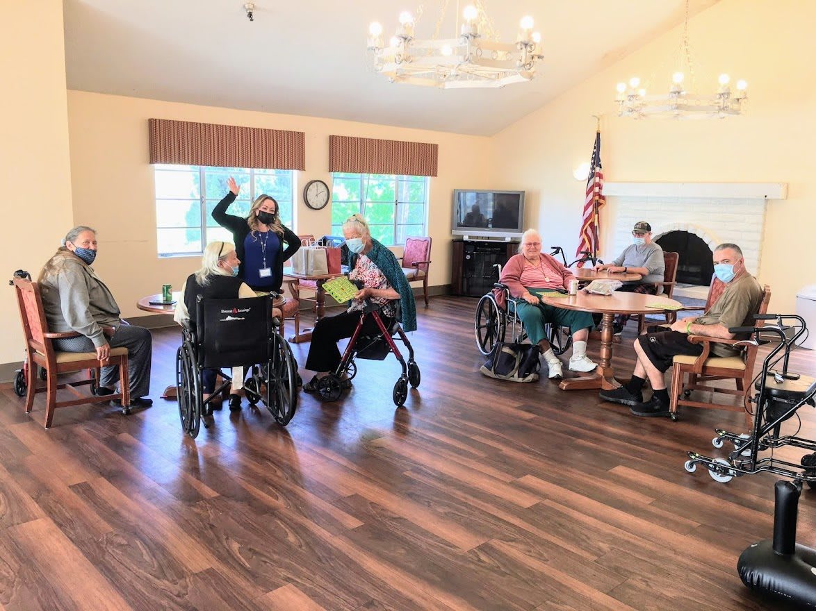 A group of seniors engaged in activities at a community center, with an American flag displayed in the room.