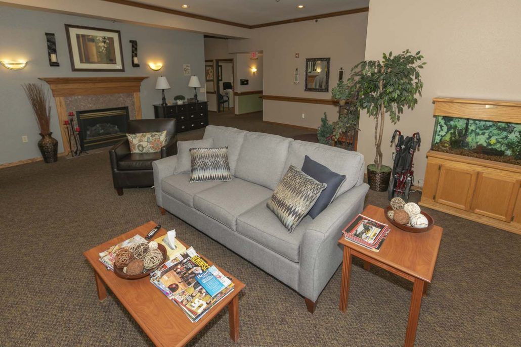 A cozy living room with a sofa, coffee table adorned with magazines, and a fireplace in the background.