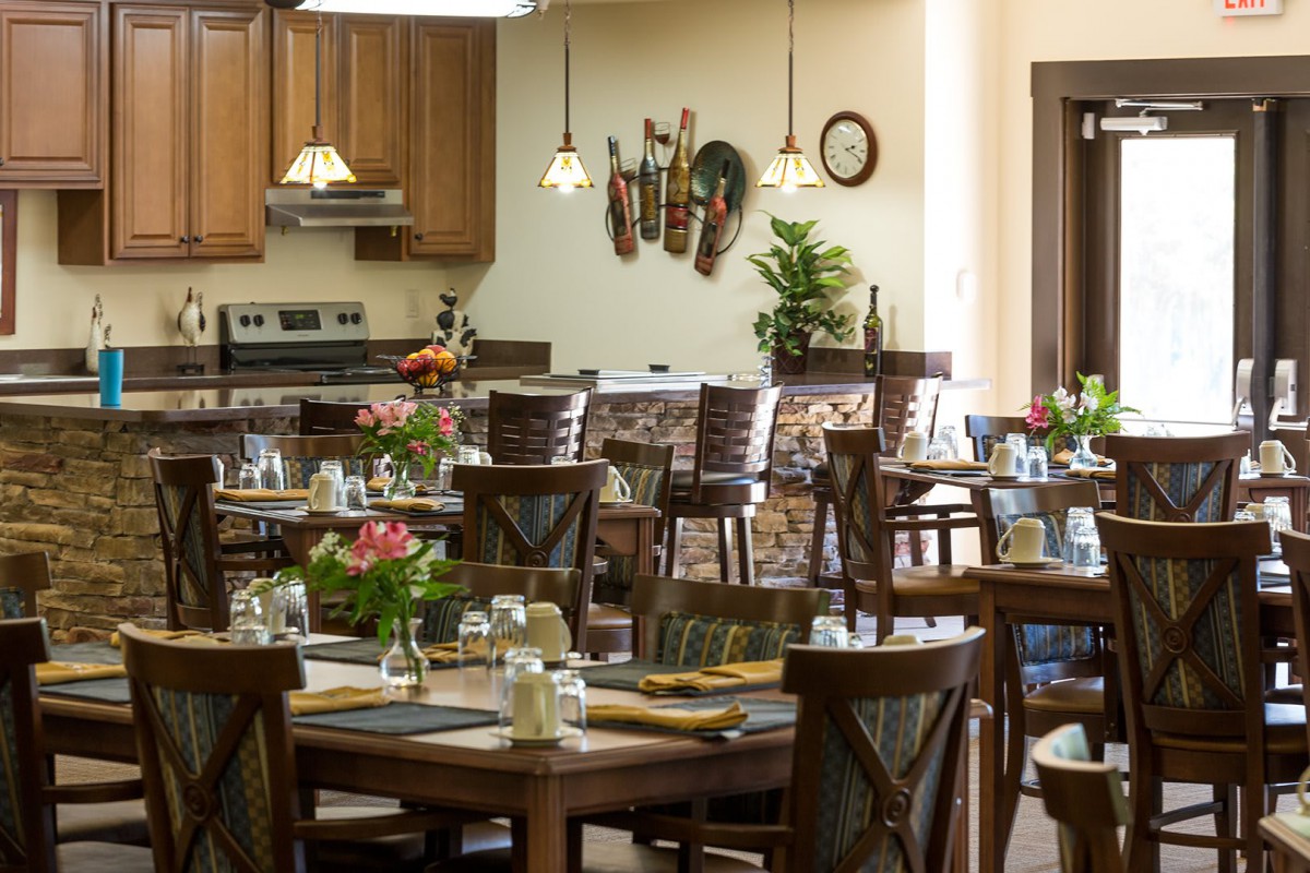 A cozy restaurant interior with neatly arranged tables and chairs, warm lighting, and decorative elements on the walls.