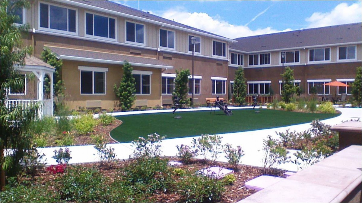 A modern residential building with a landscaped courtyard and grass.