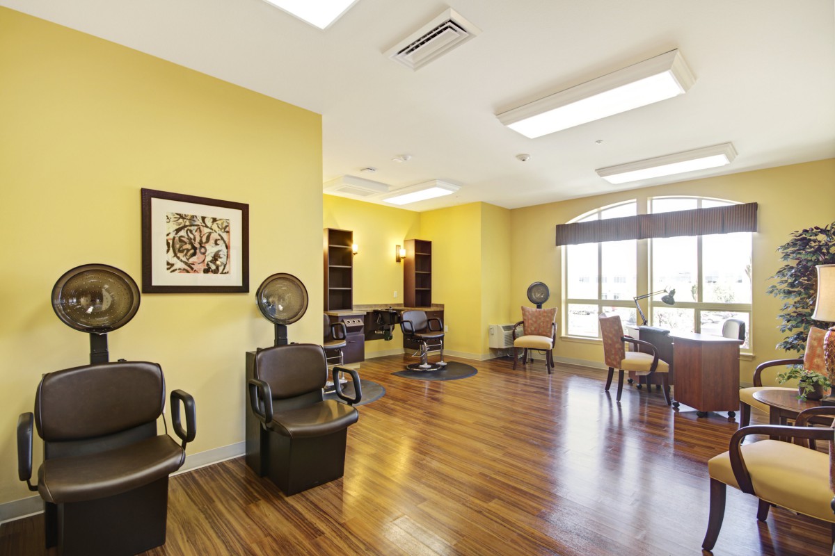 A bright salon interior with chairs and hairdryers, featuring yellow walls and natural lighting.
