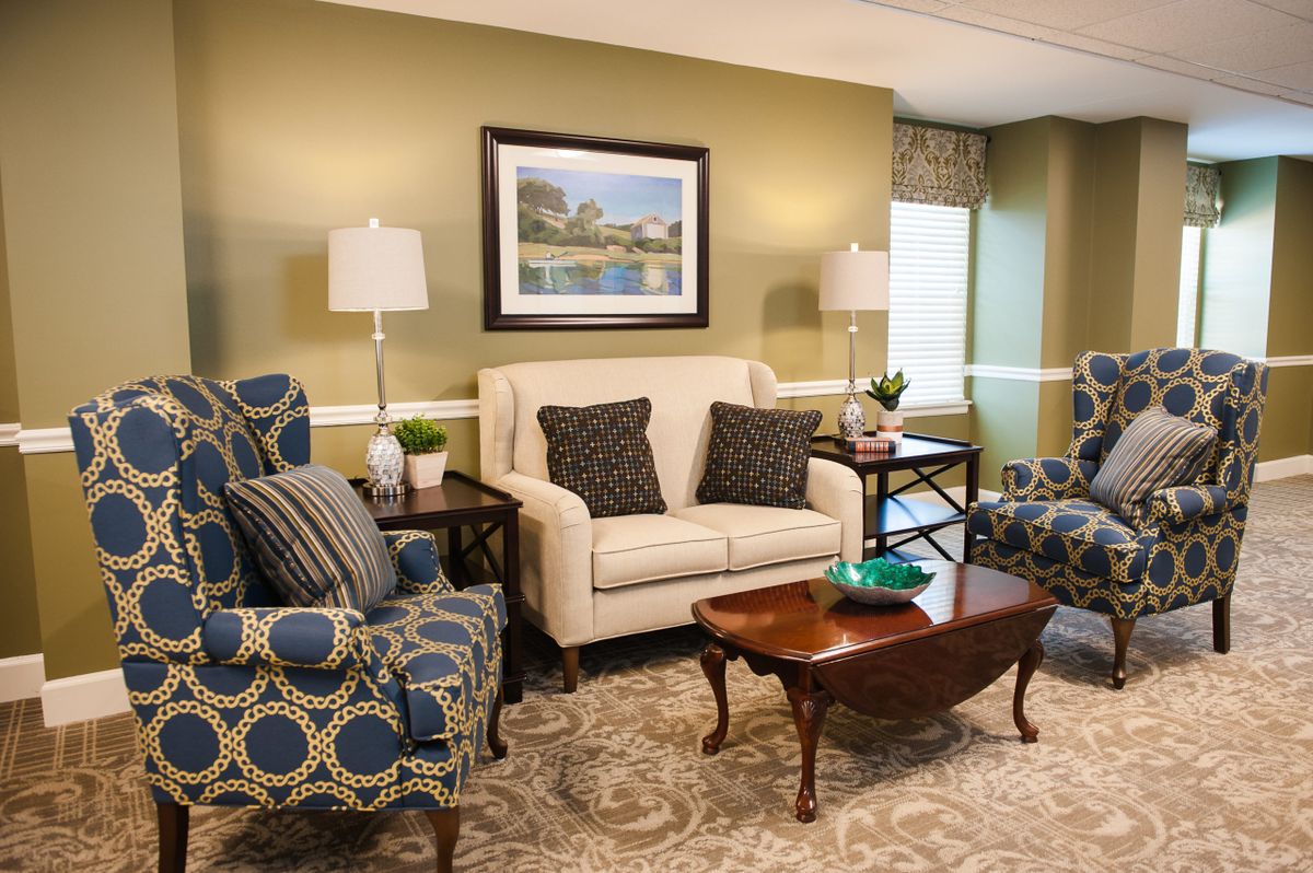 A cozy living room with a sofa and patterned armchairs, featuring a wooden coffee table and decorative lamps.