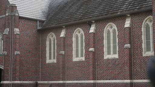 The intricate design of a brick church featuring gothic-style windows.