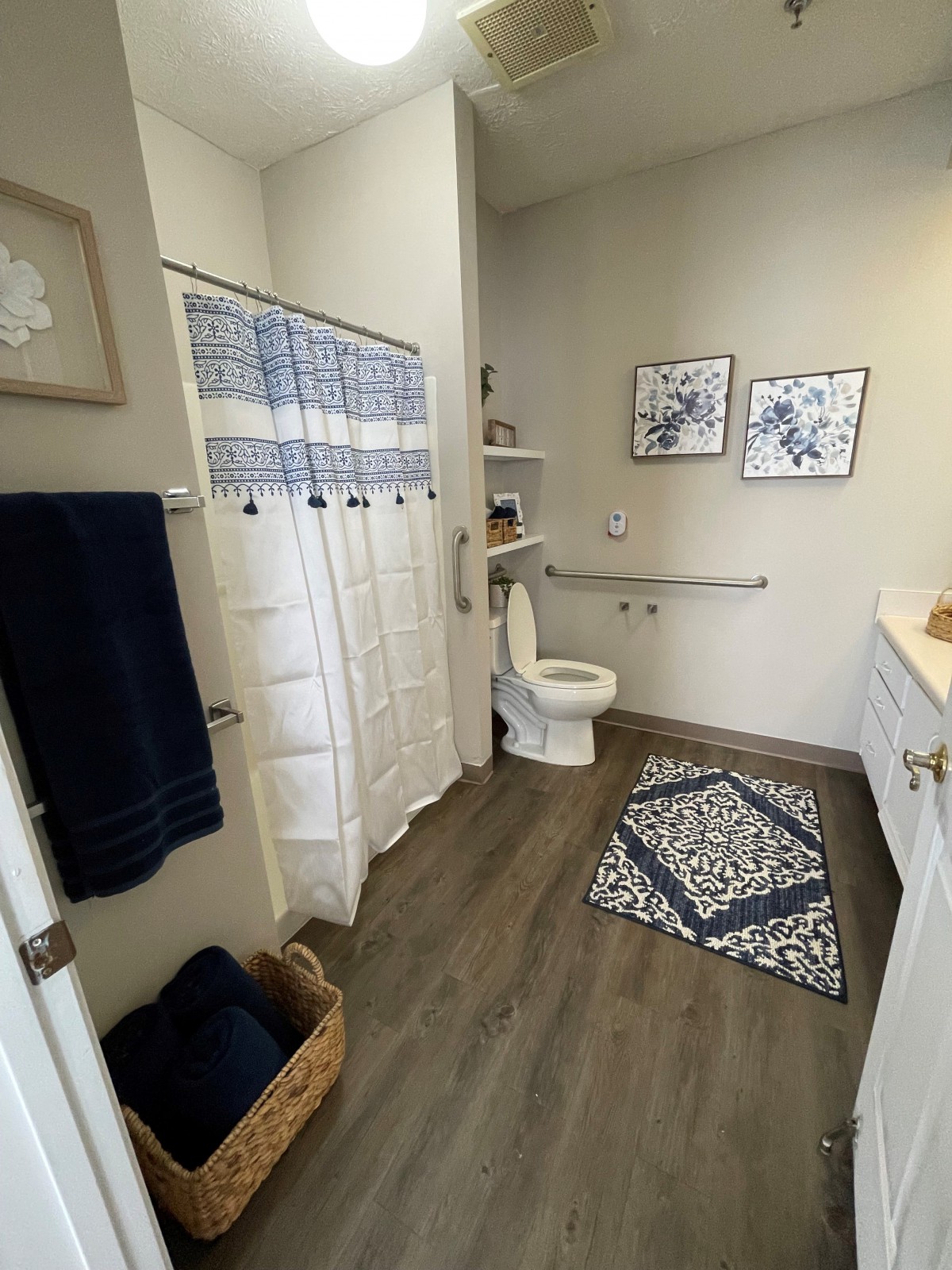 A modern bathroom with blue and white decor, featuring a shower, toilet, and open shelving.