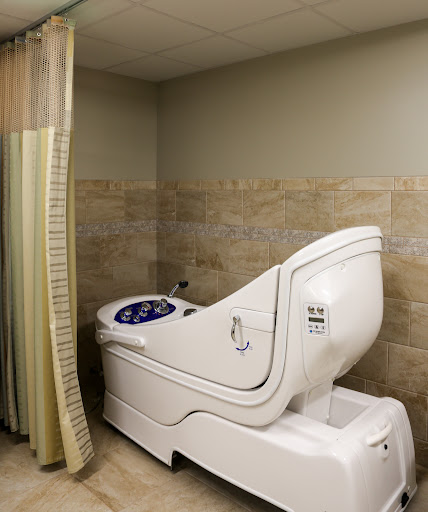A specialized toilet designed for healthcare settings, equipped with a privacy curtain.
