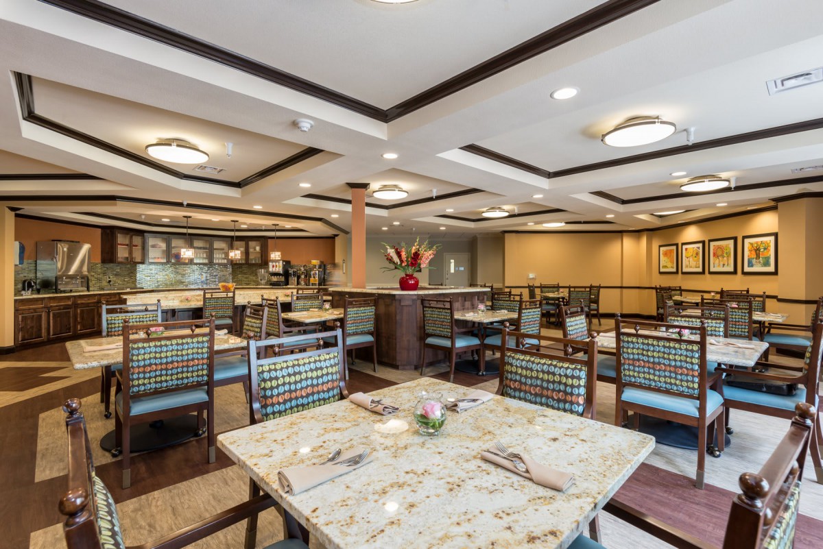 A spacious dining area with neatly arranged tables and chairs, featuring modern lighting and decor.