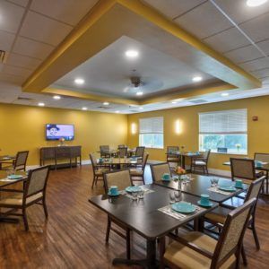 A cozy dining area with tables and chairs, featuring a television on the wall.