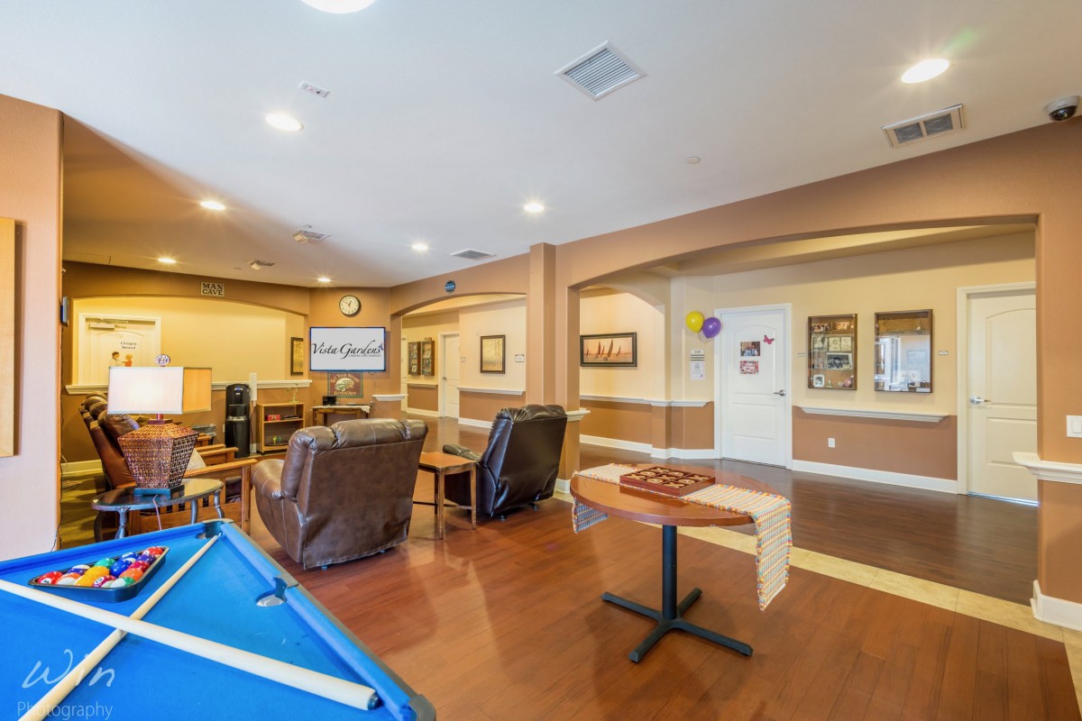 A cozy game room with a pool table, comfortable lounge chairs, and a television.