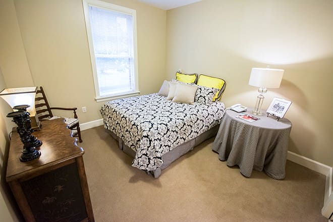 A cozy bedroom with a bed, side table, and a window.