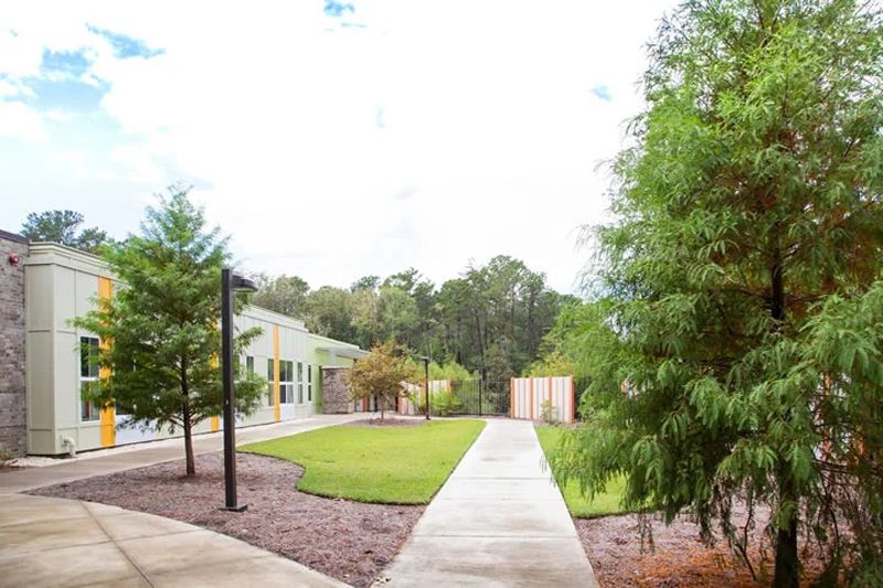A landscaped outdoor area with a pathway leading through grass and trees.