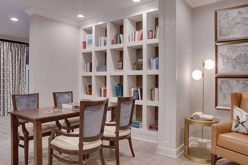 A cozy library corner with a table, chairs, and bookshelves.