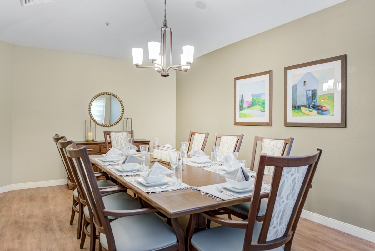 A modern dining room with a long table set for guests.