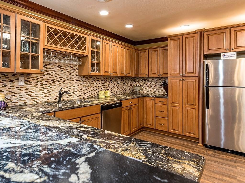A modern kitchen featuring wooden cabinets, a granite countertop, and stainless steel appliances.