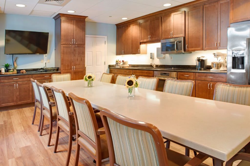 A spacious kitchen and dining area with a long table, chairs, and wooden cabinets.