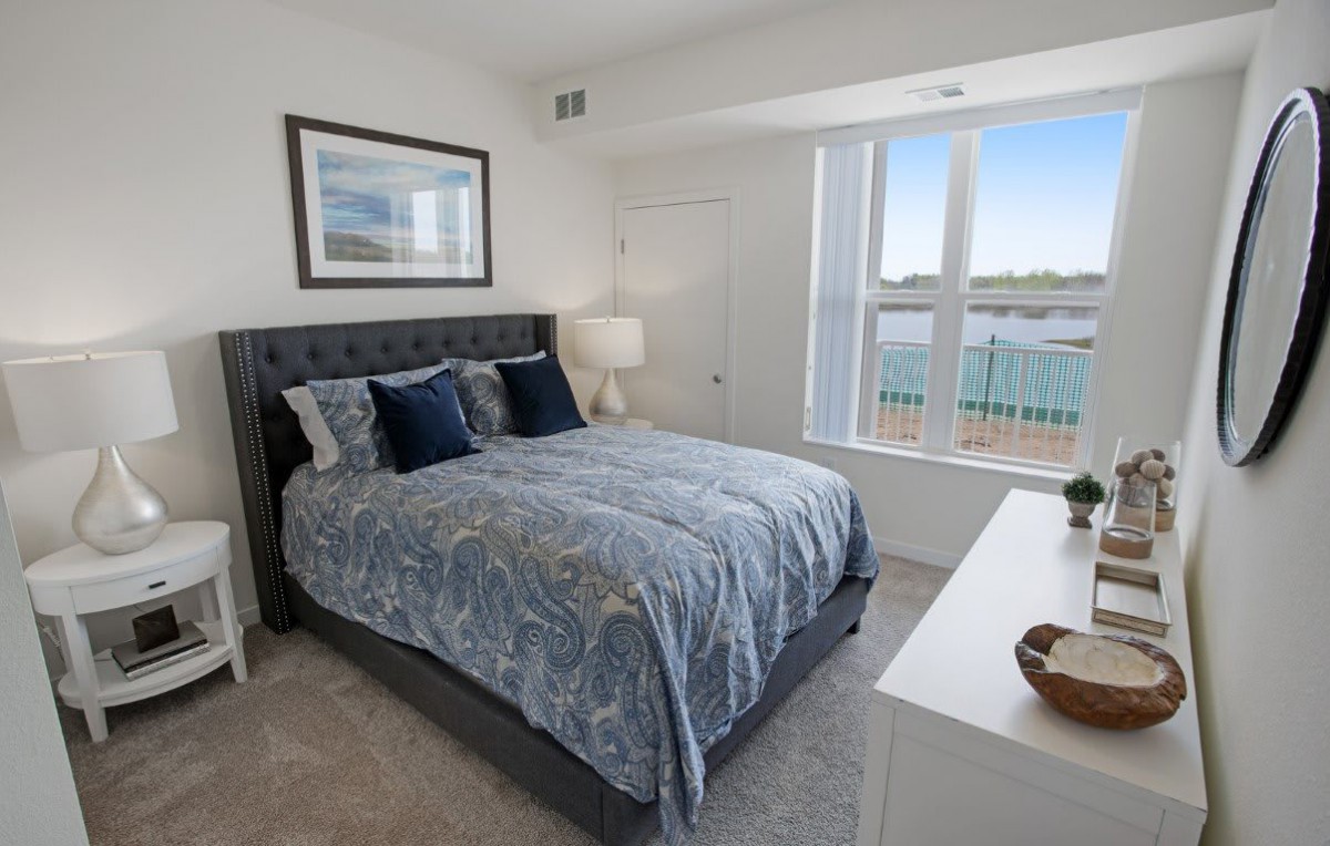 A cozy bedroom with a large bed, stylish bedding, and a bright window view.