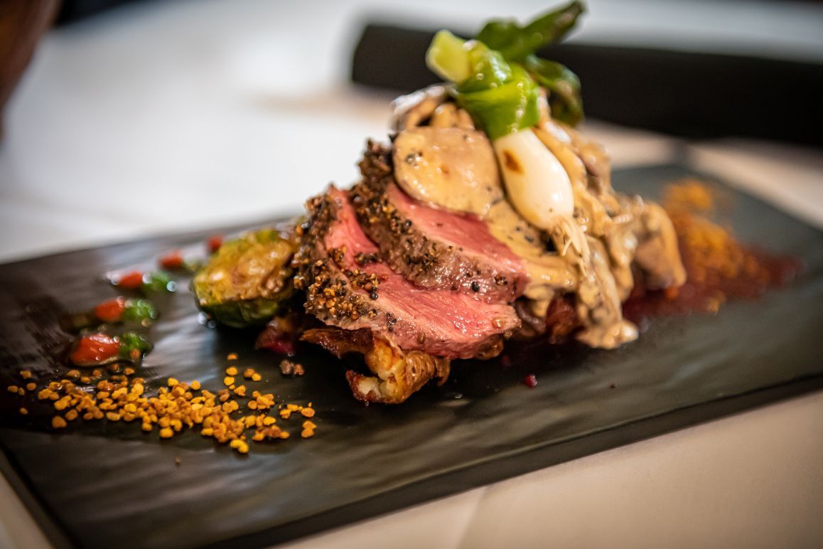 A beautifully plated gourmet steak dish with herbs and vegetables.