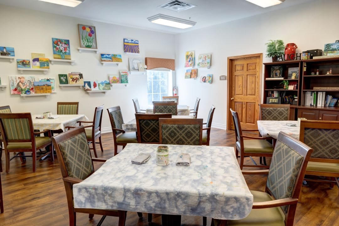 A cozy dining area with tables and chairs, decorated with artwork on the walls.