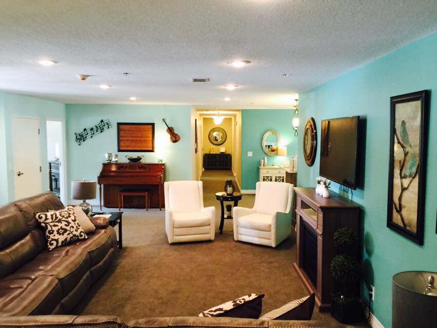 A cozy living room featuring a piano and guitar, with comfortable seating and vibrant decor.