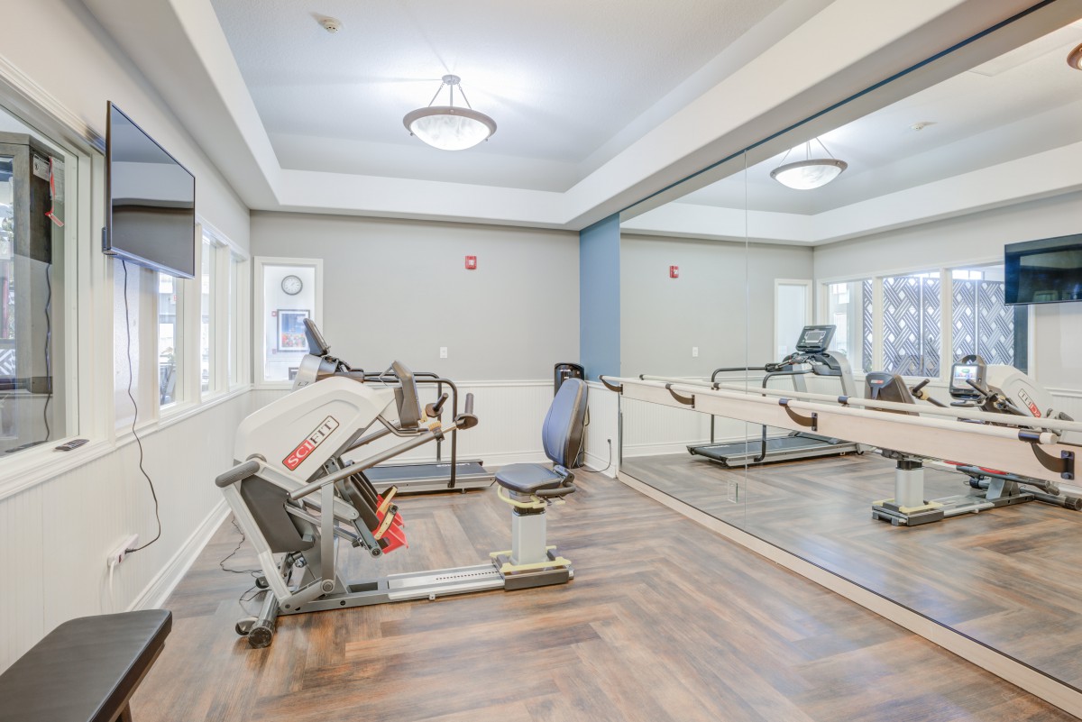 A modern gym with exercise machines and mirrored walls.