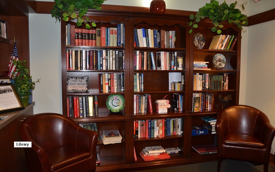 A cozy home library with a wooden bookshelf filled with books and decorative items.
