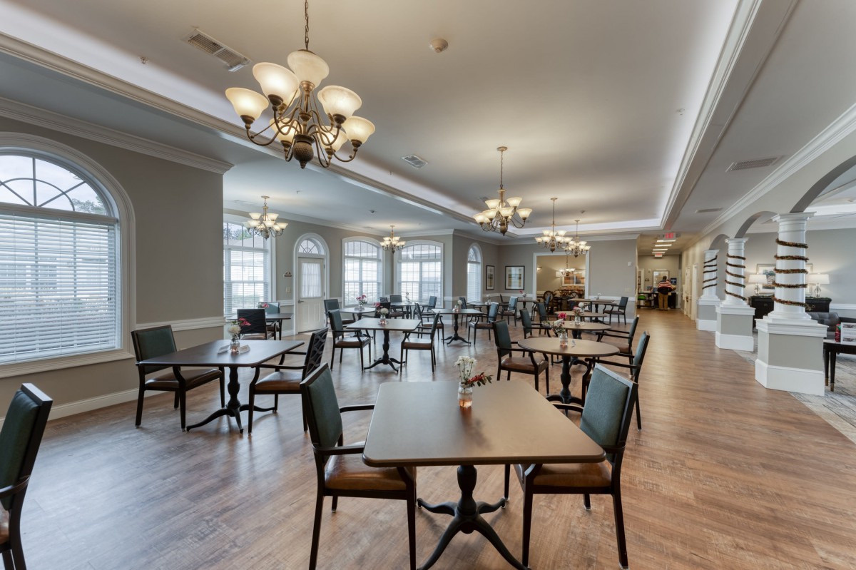 A spacious dining room featuring elegant chandeliers and neatly arranged tables and chairs.