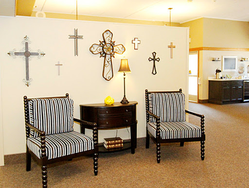 A cozy living area featuring striped chairs, a decorative lamp, and various crosses on the wall.