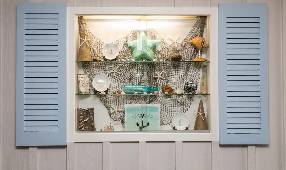 A nautical-themed shelf display featuring starfish, seashells, and an anchor accent.