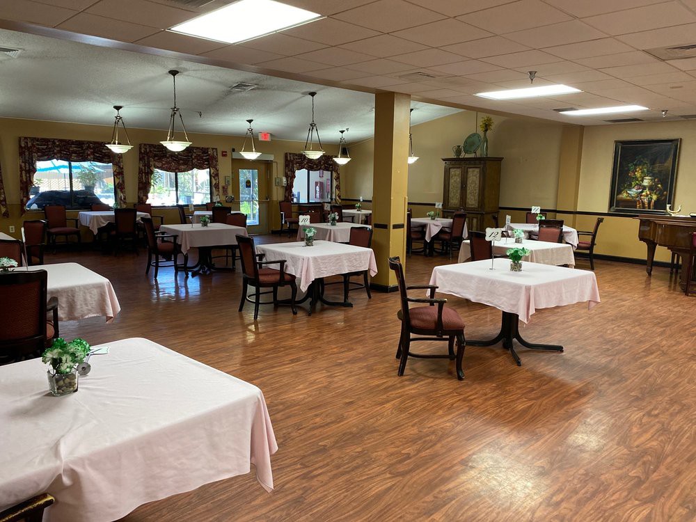 An empty dining room with tables covered in white linens, ready for service.