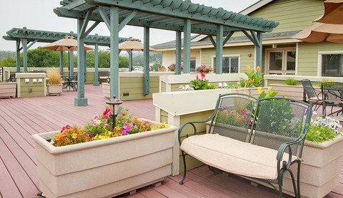 A charming patio area with a pergola, seating, and vibrant flower planters.