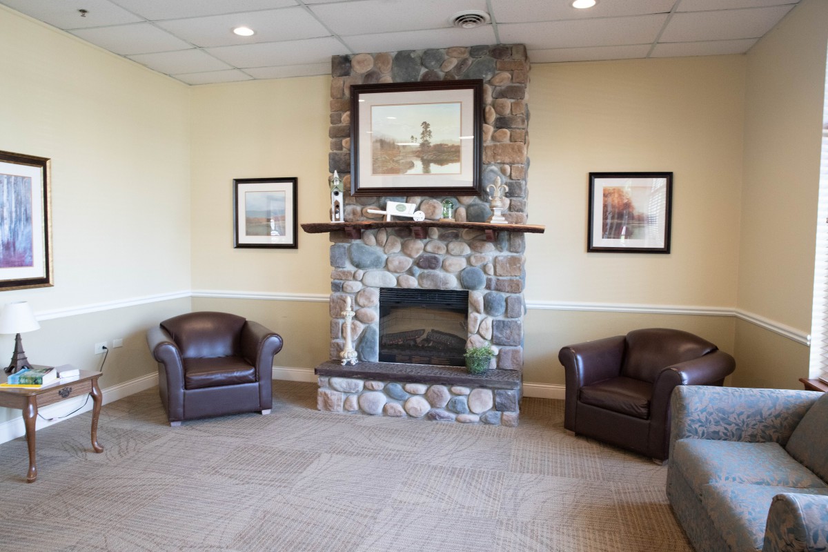 A cozy living room with a stone fireplace and leather chairs.