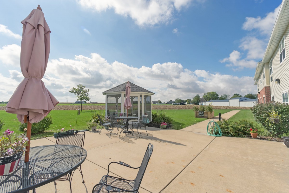 A sunny patio with outdoor seating and a gazebo, set against a cloudy sky.