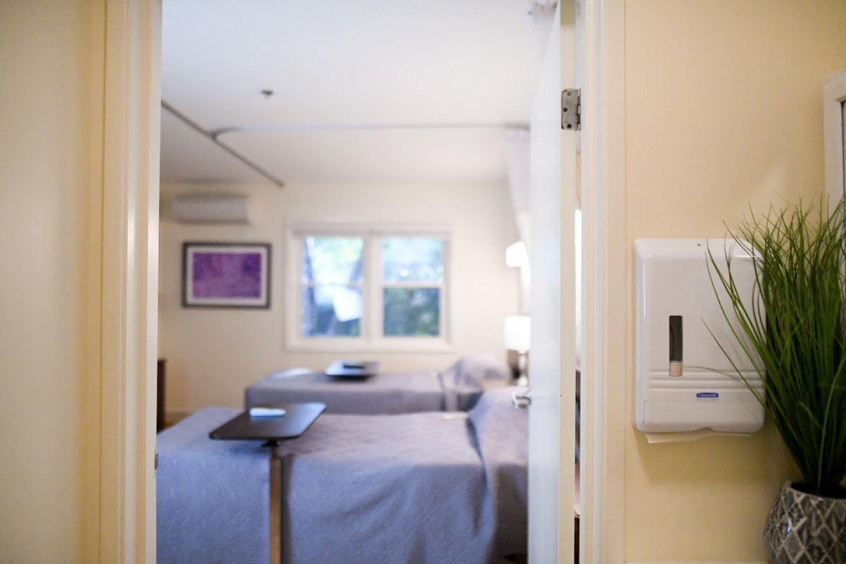 A well-lit hospital room featuring two beds and medical equipment.