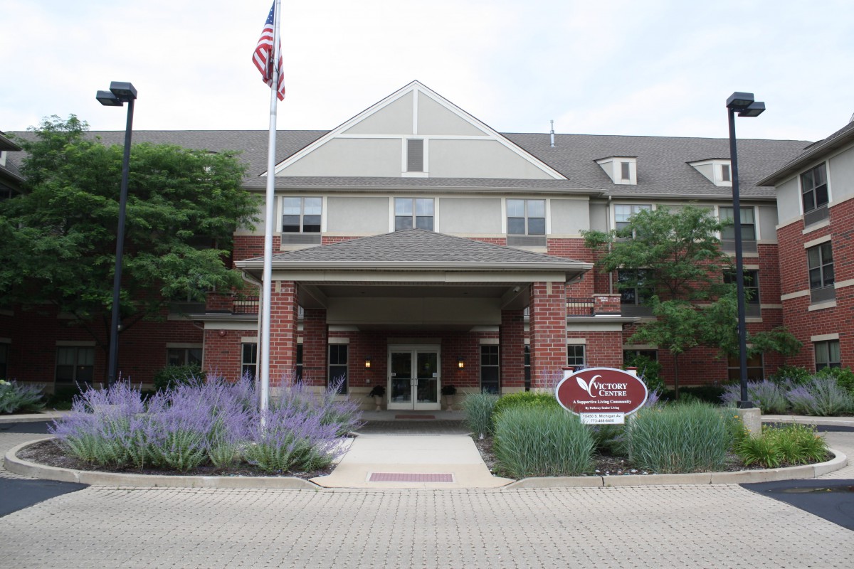 A brick building with an entrance, surrounded by landscaping and featuring a flagpole.