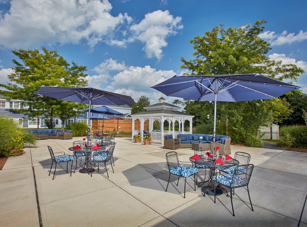 A sunny outdoor patio with tables, umbrellas, and a gazebo.