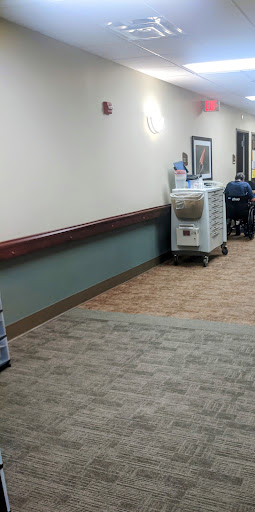 A view of a hospital hallway featuring medical equipment and seating.