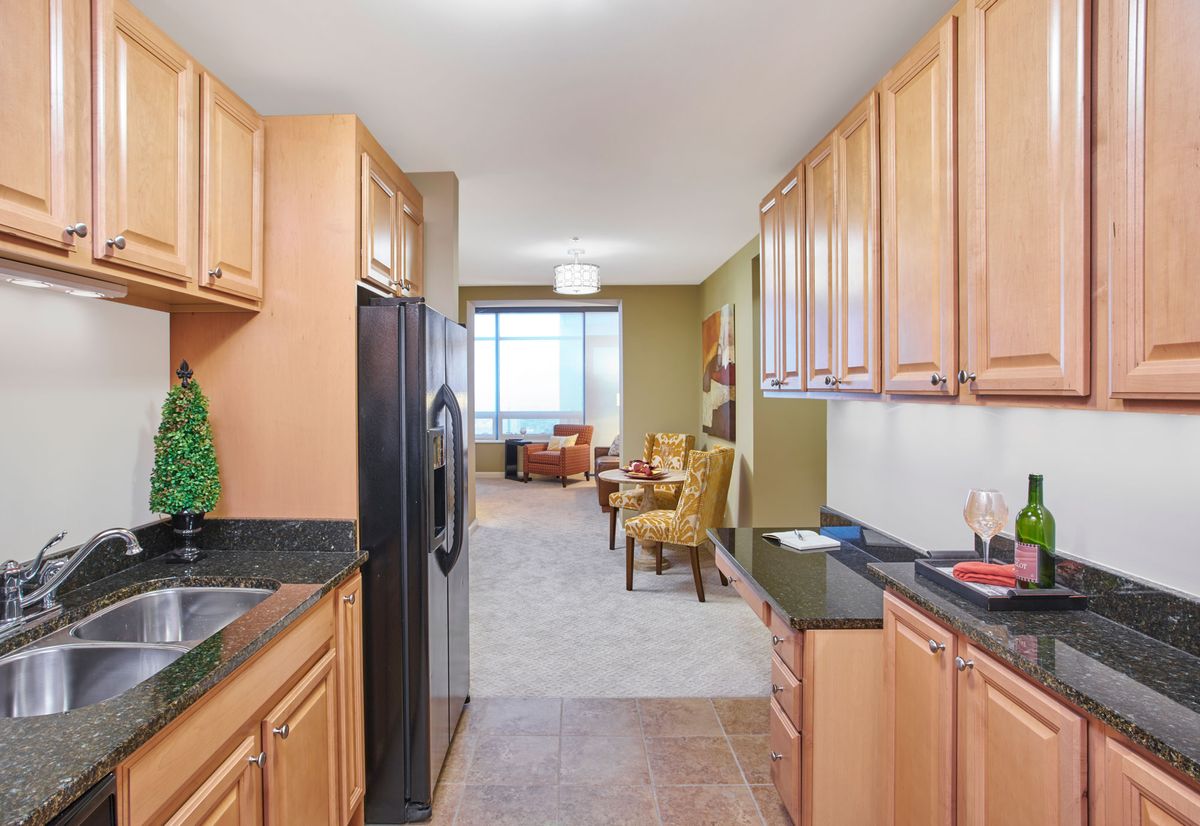 Modern kitchen with wood cabinets and granite countertops leading to an open living area.