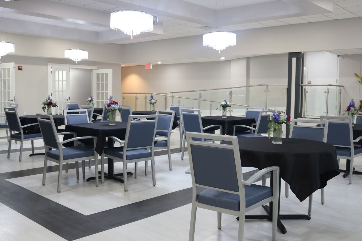 A modern dining area with neatly arranged tables and chairs under elegant lighting.