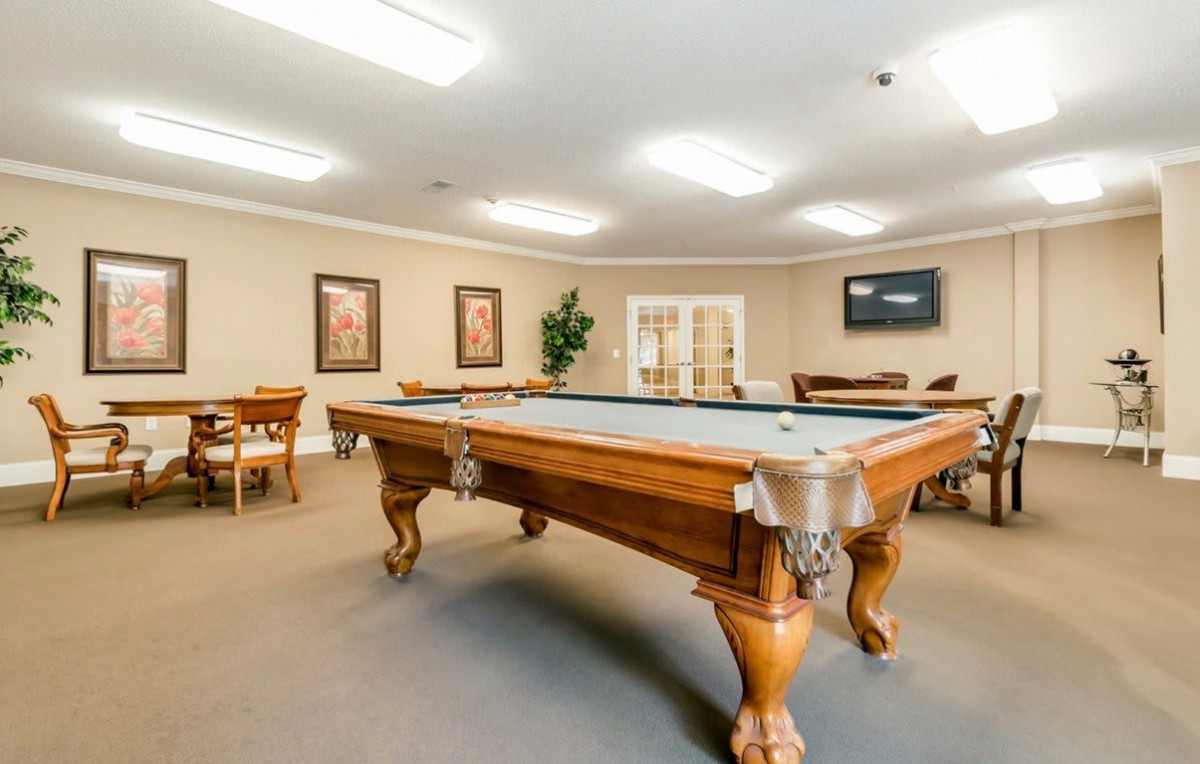 A well-lit game room featuring a classic pool table and seating area.