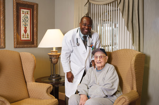 A healthcare professional posing with an elderly patient in a cozy indoor setting.