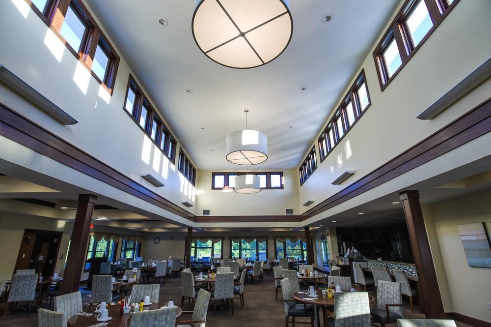 A spacious dining area with elegant lighting, tables, and chairs.