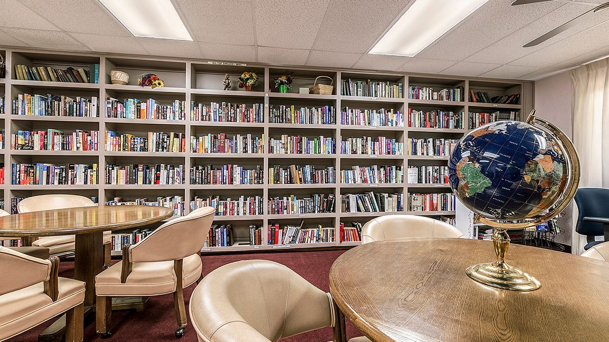 A cozy library corner with bookshelves lined with various books and a seating area for reading.