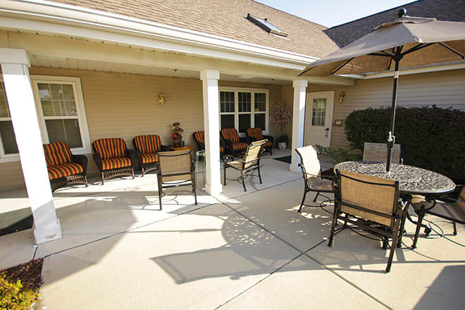A sunny outdoor patio with chairs and tables, featuring an umbrella for shade.