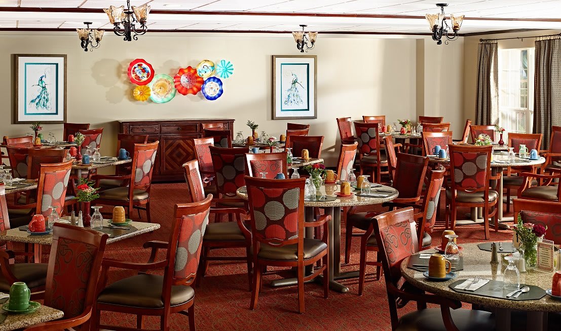 A cozy restaurant dining area with neatly arranged tables and chairs, featuring colorful wall art.