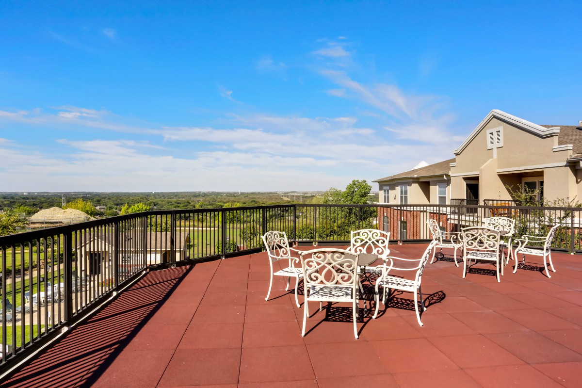 A spacious outdoor terrace with tables and chairs, overlooking a scenic view.