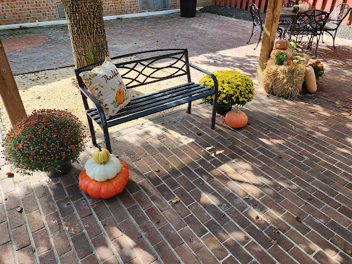 A cozy outdoor setting with a decorative bench surrounded by autumn-themed elements like pumpkins and flowers.