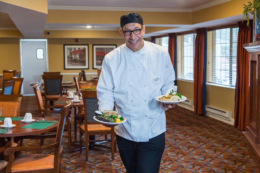 A chef in a restaurant serving two dishes.